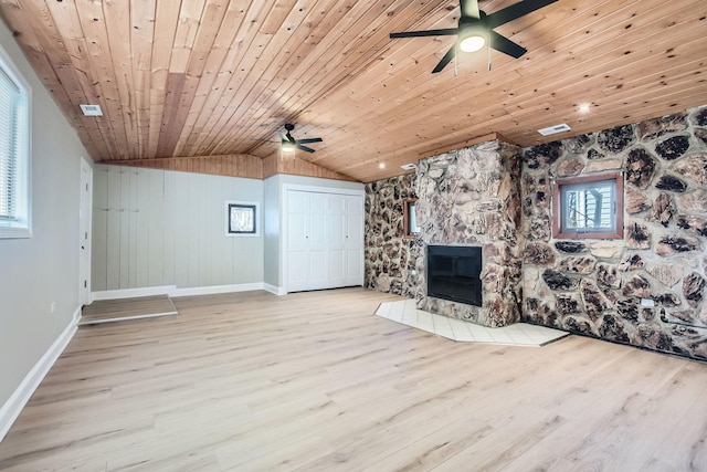 unfurnished living room featuring lofted ceiling, a stone fireplace, wood ceiling, light hardwood / wood-style flooring, and ceiling fan