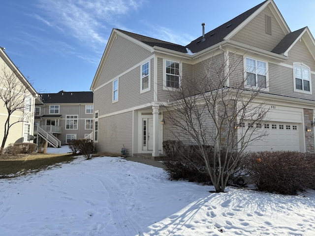 snow covered property with a garage