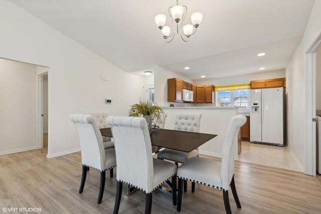 dining space with a notable chandelier and light hardwood / wood-style flooring