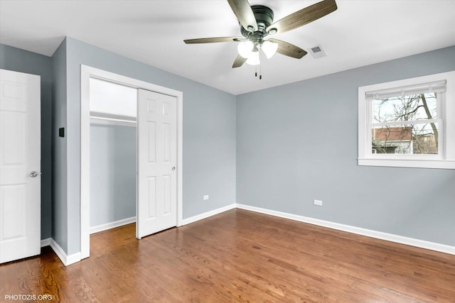 unfurnished bedroom with a closet, dark hardwood / wood-style floors, and ceiling fan