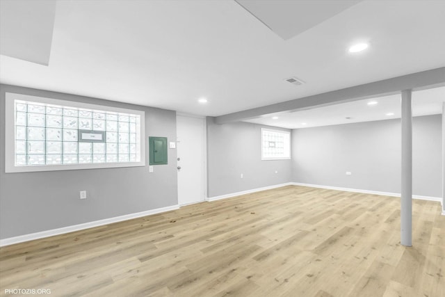 basement featuring light hardwood / wood-style flooring and electric panel