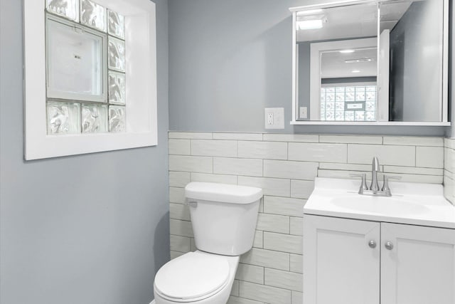 bathroom featuring vanity, tile walls, and toilet