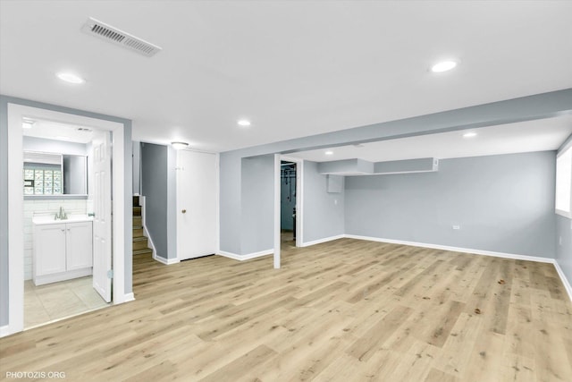 basement with sink and light wood-type flooring