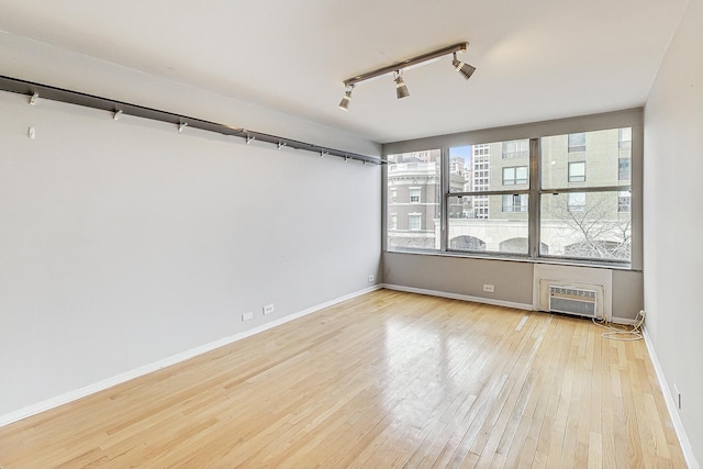 spare room with rail lighting, an AC wall unit, and light hardwood / wood-style flooring