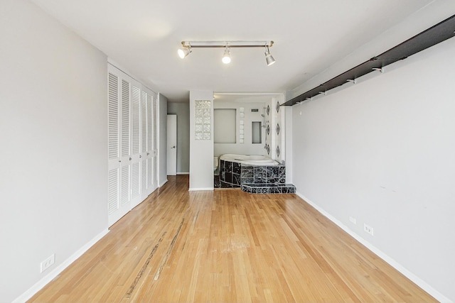 unfurnished bedroom with rail lighting and hardwood / wood-style floors