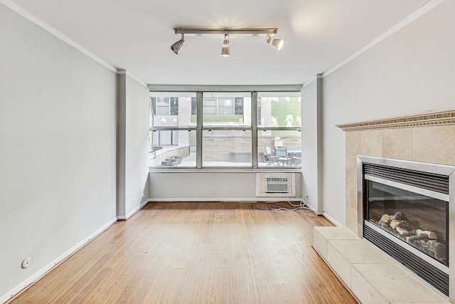 unfurnished living room with crown molding, a tiled fireplace, light hardwood / wood-style floors, and an AC wall unit