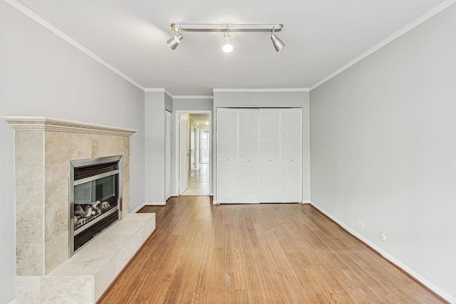 unfurnished living room with a tile fireplace, ornamental molding, and hardwood / wood-style floors