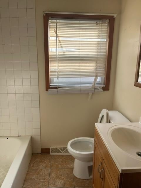 bathroom featuring vanity, toilet, tile patterned floors, and a tub to relax in