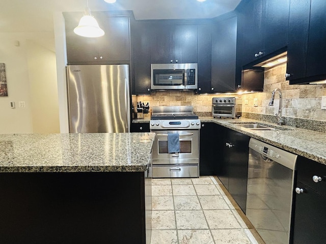 kitchen with tasteful backsplash, appliances with stainless steel finishes, sink, and pendant lighting