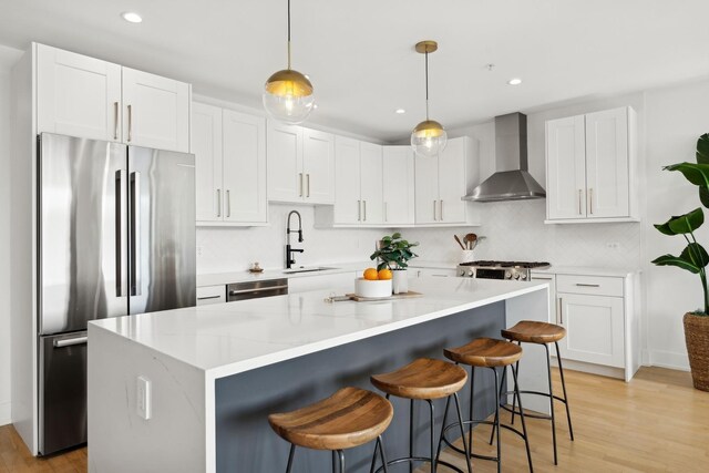 kitchen featuring pendant lighting, white cabinetry, high end stainless steel range, and light hardwood / wood-style flooring