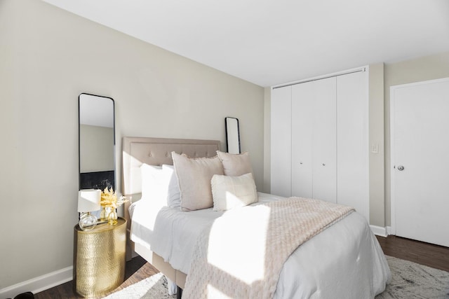 bedroom with dark hardwood / wood-style floors and a closet