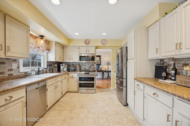 kitchen with stainless steel appliances, tasteful backsplash, sink, and light tile patterned flooring