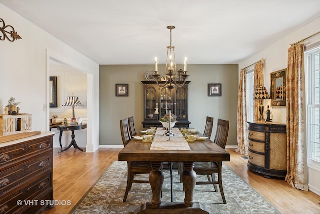 dining space with plenty of natural light, an inviting chandelier, and light hardwood / wood-style floors