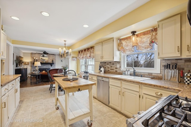 kitchen featuring a fireplace, appliances with stainless steel finishes, decorative light fixtures, and cream cabinetry