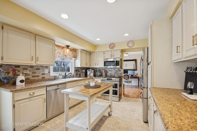 kitchen featuring appliances with stainless steel finishes, sink, light tile patterned floors, and backsplash