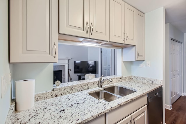 kitchen featuring dark hardwood / wood-style floors, a fireplace, dishwasher, sink, and light stone countertops