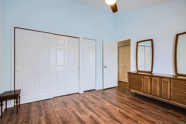 bedroom with dark hardwood / wood-style flooring, two closets, and ceiling fan