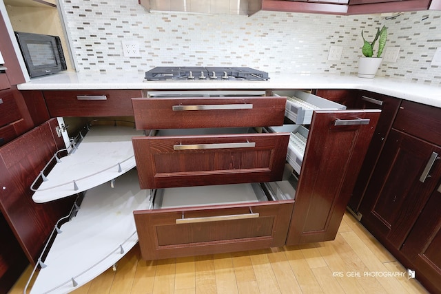 room details with tasteful backsplash, stainless steel gas cooktop, and light hardwood / wood-style flooring