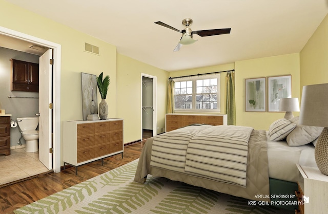 bedroom with ensuite bathroom, dark hardwood / wood-style floors, a walk in closet, ceiling fan, and a closet