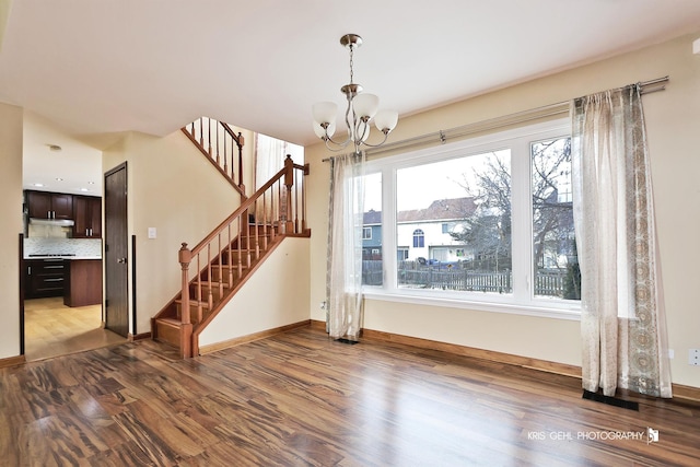 unfurnished living room with light wood-type flooring, a wealth of natural light, and an inviting chandelier