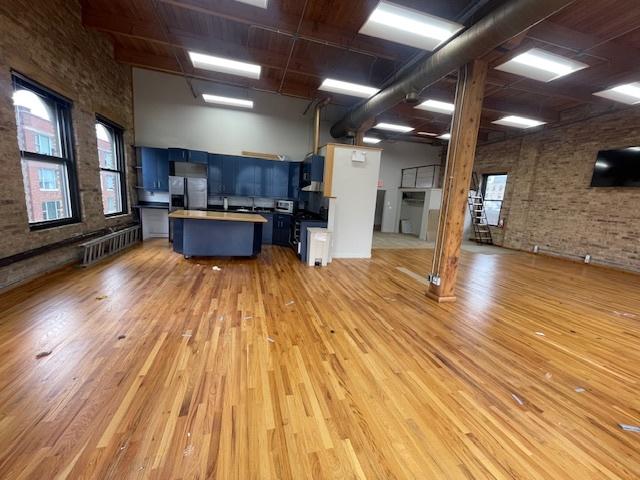 kitchen featuring brick wall, a breakfast bar, blue cabinets, a center island, and stainless steel fridge with ice dispenser