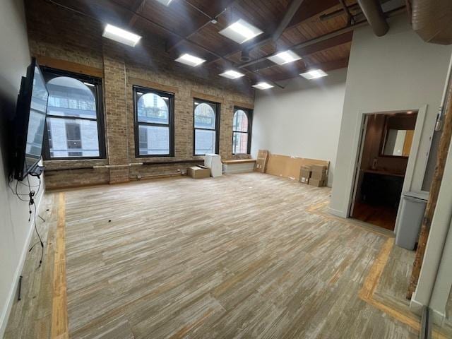 empty room featuring brick wall, hardwood / wood-style floors, wooden ceiling, and beam ceiling