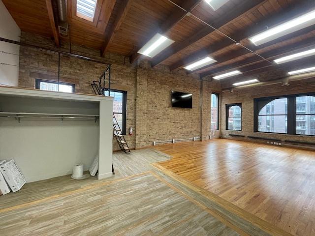 interior space with brick wall, wood-type flooring, wooden ceiling, and plenty of natural light