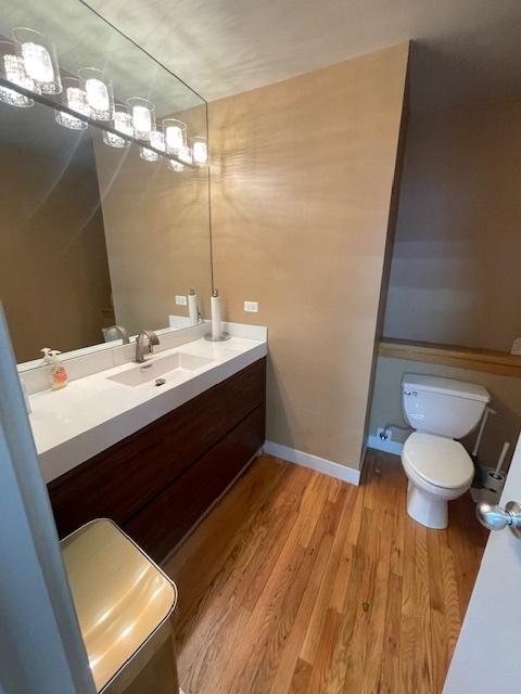 bathroom with wood-type flooring, toilet, and vanity