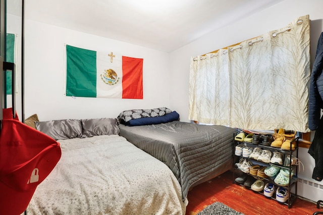 bedroom with hardwood / wood-style flooring and a baseboard heating unit