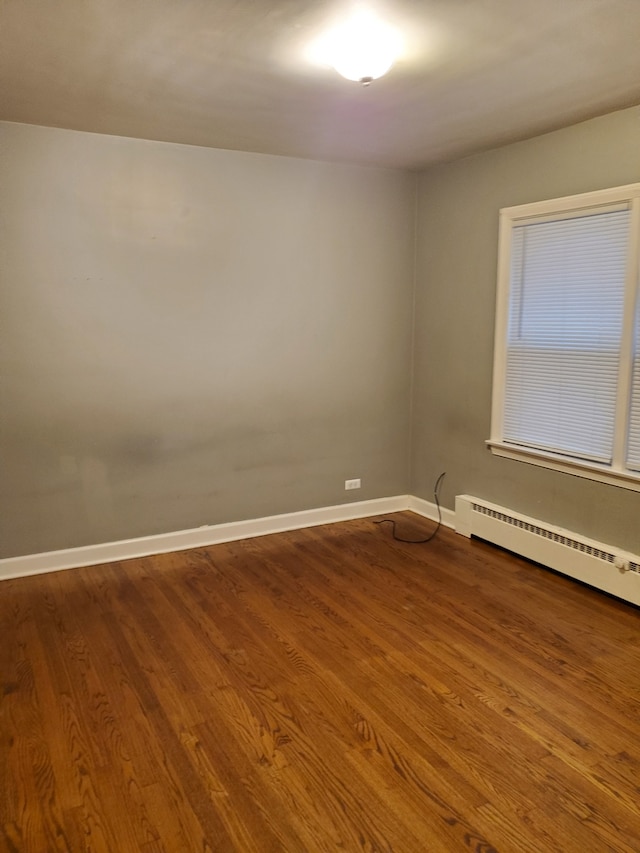 empty room featuring hardwood / wood-style floors and a baseboard heating unit