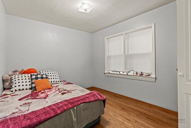 bedroom with hardwood / wood-style flooring and a baseboard heating unit