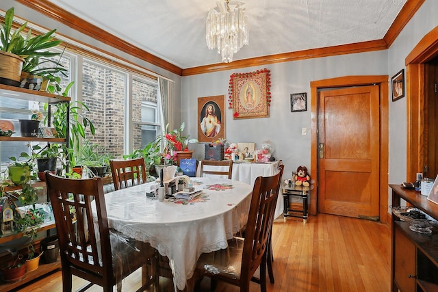 dining area with ornamental molding, an inviting chandelier, a textured ceiling, and light wood-type flooring