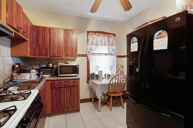 kitchen featuring light tile patterned flooring, sink, black fridge, range with gas stovetop, and ceiling fan