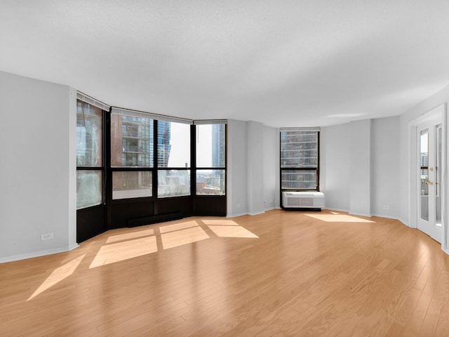 unfurnished living room with light wood-style floors, radiator heating unit, a textured ceiling, and baseboards