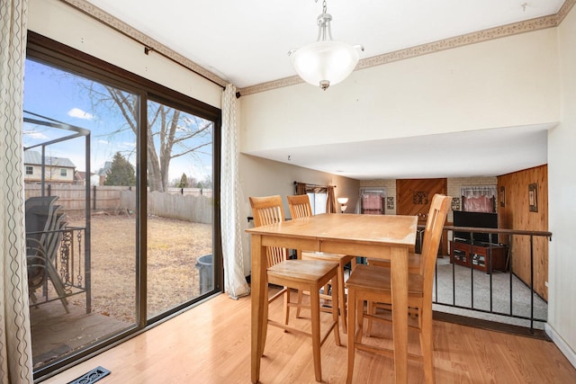 dining area with wood finished floors, visible vents, and wooden walls