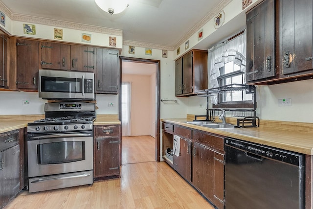 kitchen with a sink, light wood-style floors, stainless steel appliances, and light countertops