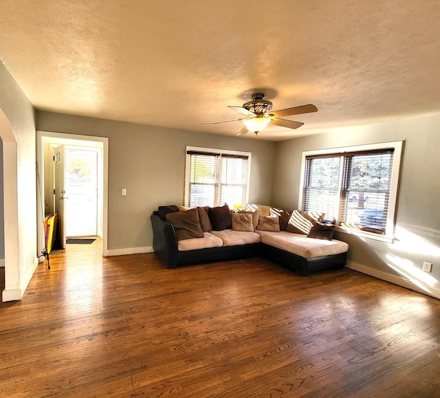 unfurnished living room with ceiling fan, dark hardwood / wood-style flooring, and a textured ceiling