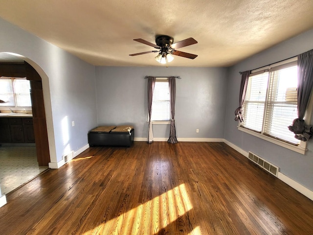 spare room with a textured ceiling, plenty of natural light, dark hardwood / wood-style floors, and ceiling fan