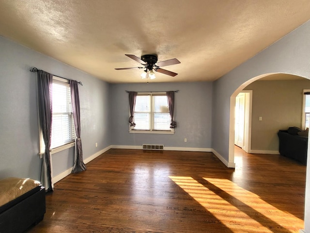 unfurnished room featuring ceiling fan, plenty of natural light, and dark hardwood / wood-style floors