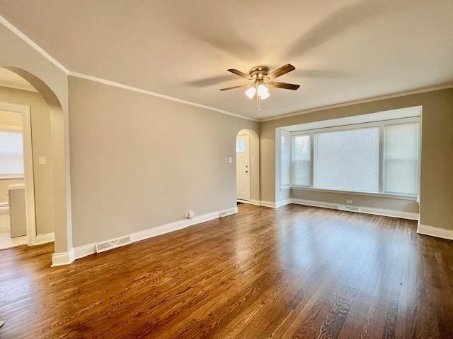 empty room with crown molding, ceiling fan, and dark hardwood / wood-style floors