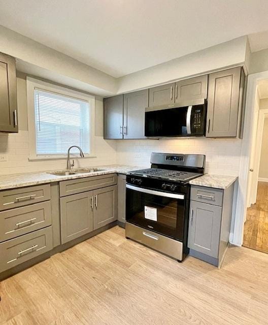 kitchen with gray cabinets, sink, stainless steel gas range, and light hardwood / wood-style floors