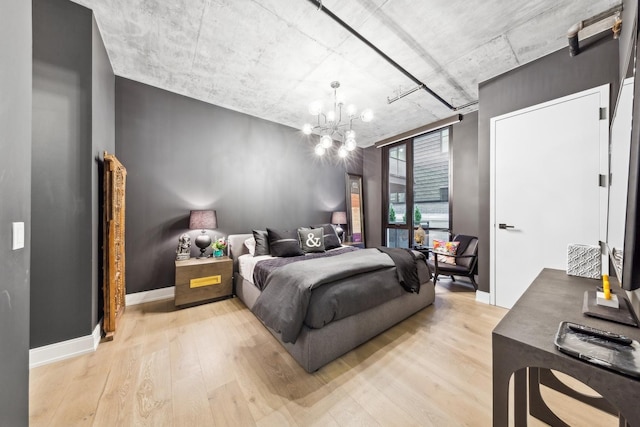 bedroom with a notable chandelier and light wood-type flooring