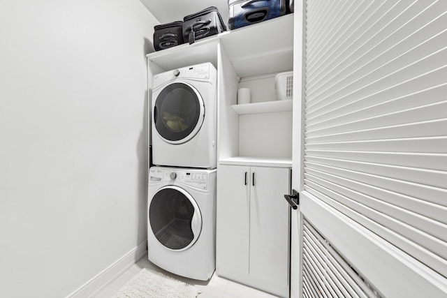 laundry room featuring cabinets, stacked washer and clothes dryer, and light tile patterned floors