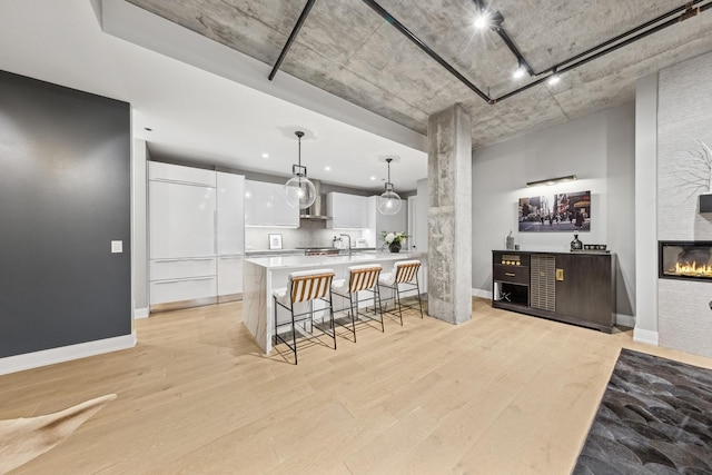 kitchen with white cabinetry, pendant lighting, light hardwood / wood-style floors, and a breakfast bar