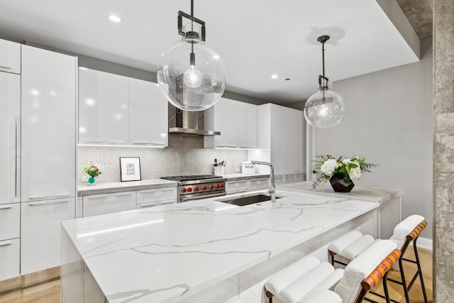 kitchen with white cabinetry, sink, pendant lighting, and high end stainless steel range