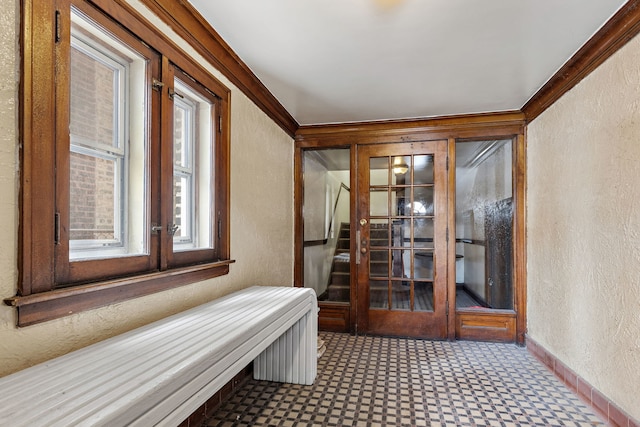 interior space featuring crown molding, a textured wall, and baseboards