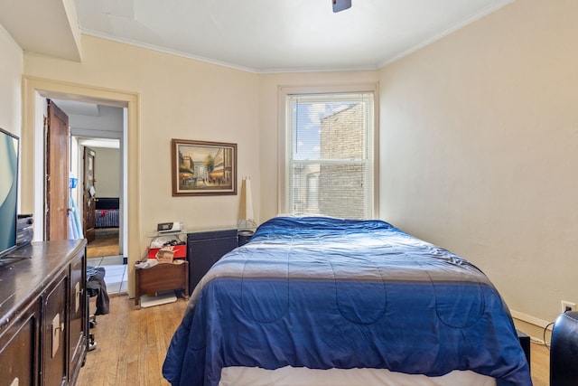 bedroom featuring baseboards, ornamental molding, and light wood finished floors