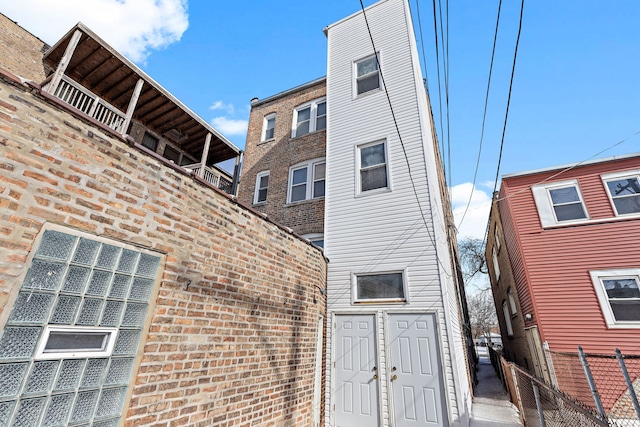 back of house featuring fence and brick siding