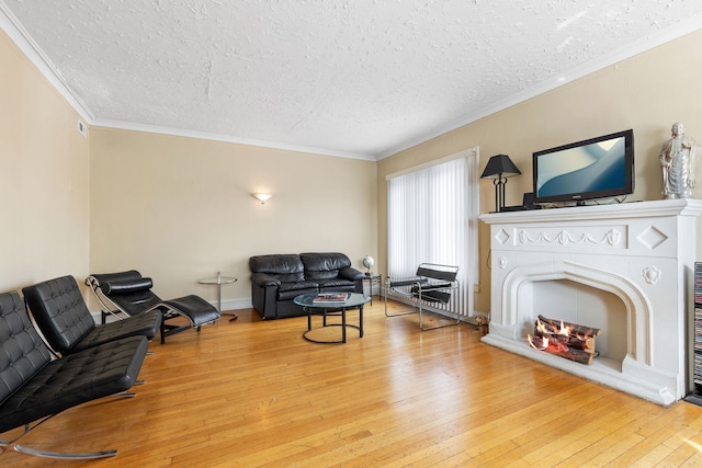 living room with wood-type flooring, a textured ceiling, a lit fireplace, and crown molding