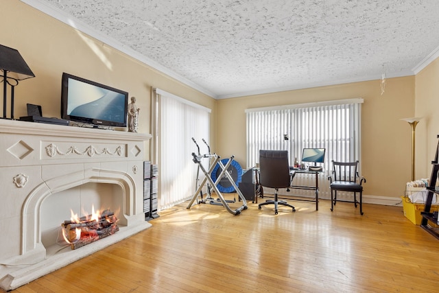 interior space featuring baseboards, a tile fireplace, hardwood / wood-style flooring, a textured ceiling, and crown molding